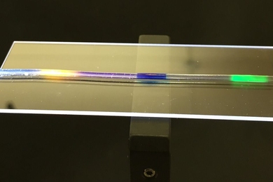 MIT researchers have developed a stretchy optical fiber in which they have injected multiple organic dyes (yellow, blue, and green regions). In addition to lighting up, the dyes act as a strain sensor, enabling researchers to quantify where and by how much a fiber has been stretched. 