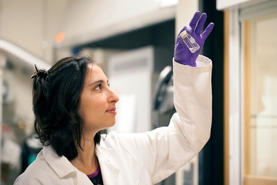 Graduate student Ingrid Guha holds a jar containing a clear liquid that looks like water to the naked eye, but it’s actually an emulsion of oil and water at the nanoscale. 

