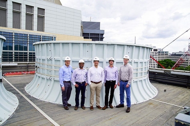 On the roof of the Central Utility Plant building, standing in front of one of the cooling towers, are (left to right): Seth Kinderman, Central Utility Plant engineering manager; Kripa Varanasi, associate professor of mechanical engineering; recent doctoral graduates Karim Khalil and Maher Damak; and Patrick Karalekas, plant engineer, Central Utilities Plant.
