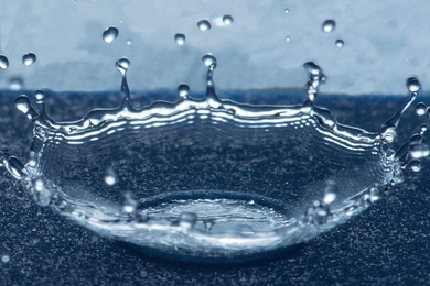 Droplets that land on a specially prepared surface with tiny ring-shaped patterns splash upward in a bowl shape, as seen in this photo, instead of spreading out over the surface, thus minimizing the water’s contact with the surface.