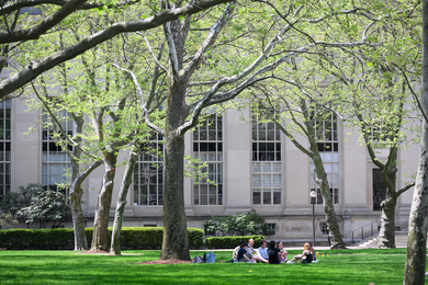 Group of students meet on the grass on campus.
