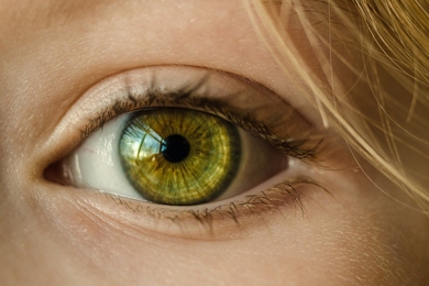 A closeup of the vibrant green eye of a woman with blond hair