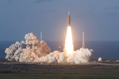 Evening photo of Artemis II launching by a large body of water