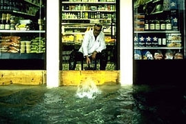 A Venetian grocer wears waders while minding the store.