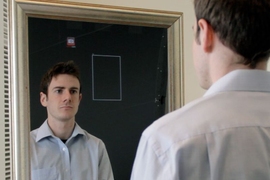 MIT Media Lab student Daniel McDuff, who collaborated on the pulse-monitoring system, demonstrates a version of the device built into a mirror that displays his pulse rate in real-time at the bottom.