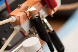 A sample of 'Cambridge crude' — a black, gooey substance that can power a highly efficient new type of battery. A prototype of the semi-solid flow battery is seen behind the flask. 