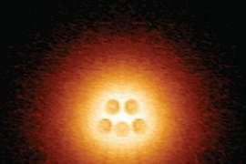 Scanning tunneling microscope image shows an artificial atomic nucleus on graphene, consisting of five pairs of calcium atoms (slightly darker circles at center), in an electron cloud that is on the verge of collapse.