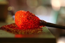 Photo of molten red glass in a blob at the end of a pole