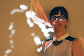Architecture student Paloma Gonzalez Rojas standing in front of WalkAcross, her project that displays a real-time visualization of visitors' motion in the MIT Museum.