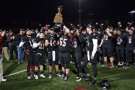 MIT players hold up the New England Football Conference trophy.