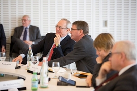 Photo of half a dozen people sitting around a table in a white conference room