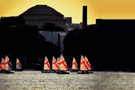 On a summer's day MIT sailboats can be seen backlit by the setting sun.