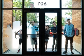 Innovators from MIT Sandbox, including (l-r) Charlene Xia, Ryan Oldja, Jessica Shi, Achille Verheye, and Andrew "Kit” Kennedy, peer into the headquarters of The Engine, a combination of long-term investment, resources, and services for founders working on “tough tech” that prioritizes high-impact solutions to big problems over early profits. 