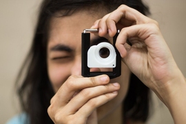Person holds up device with lens near their eye