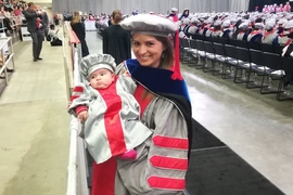 Alejandra Falla PhD '18 holds her newborn, Clara, during the 2018 Commencement exercises. 