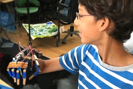 Mohan Hathi of Team Exoskeleton poses with the exo-hand built in the Engineering Design Workshop. 