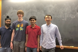 MIT Assistant Professor Yufei Zhao (far right) gave undergraduates (l-r) Mehtaab Sawhney, David Stoner, and Ashwin Sah a particularly vexing combinatorics problem. Their theorem on the number of independent sets in a graph is on the board behind them.