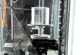 The experimental setup used to study the behavior of spider dragline silk. The cylindrical chamber at center allowed for precise control of humidity while testing the contraction and twisting of the fiber.