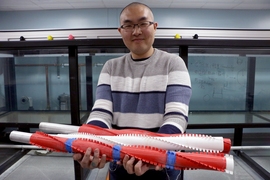 Dixia Fan stands in front of the ITT holding some of the structures towed in the tank to study VIVs, which are important for engineering offshore ocean structures like marine drilling risers that connect underwater oil wells to the surface.