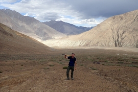 Photo of a man holding a pixaxe in the valley of a mountain range
