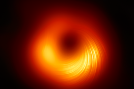 A black image features a fuzzy ring in shades of orange and yellow, with a yellow region toward the bottom featuring faint but clear spiraling lines