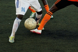 Photo of legs from two players on opposing teams juggling a soccer ball