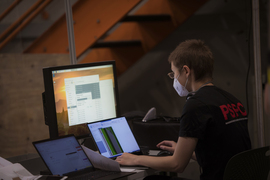 Photo of Amy Watterson working at her computer screen and wearing a face mask.