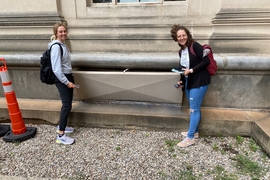 Photo of two women taking measurements outside of building vent