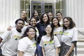 11 smiling people gather for a group photo on steps of the MIT campus