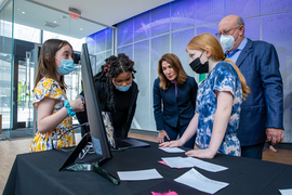 Photo of three children sharing their project on a computer screen with Karyn Polito and Jeffrey Leiden
