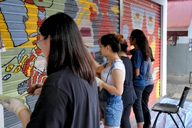 Photo of five young people painting a colorful graffiti-style mural