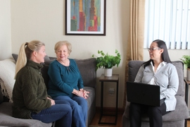 Photo of three women, one elderly and two middle-aged, talking in a living room