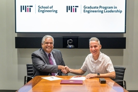 Photo of Anantha Chandrakasan shaking hands with Daniel J. Riccio, both seated at a table and smiling for the camera