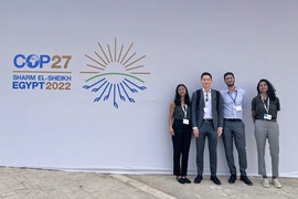 Four MIT students stand next to a sign reading “COP27, Sharm el-Sheikh, Egypt, 2022.”