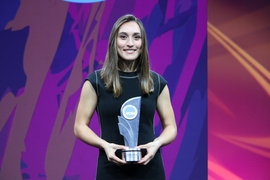 Photo of Karenna Groff holding a trophy on a colorful stage