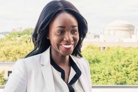Ezinne Uzo-Okoro is pictured outside, smiling and gazing off to the right. Green trees and the MIT dome are in the background