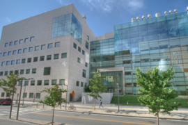 Street view of MIT Building 46, a large research building with a concrete-and-glass facade