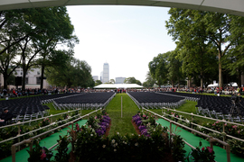 Photo of MIT's Killian Court, facing Boston, featuring hundreds of empty seats meant for new graduates, while spectators stand in the background