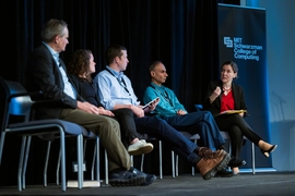 Five panelists seated on stage in discussion.