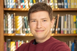 Headhshot of Mikhail Ivanov with a bookcase behind him