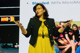 Maria Jesus Saenz speaking on a stage with images of a roadway and a team of students behind her