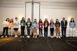 Line of 10 girls holding trophies and posing with two adults 