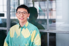 Chen Chu poses for a photo, seated in front of a glass wall