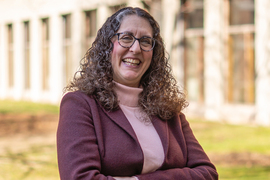 Closeup photo of Julie Greenberg on a sunny day with a brick building behind her