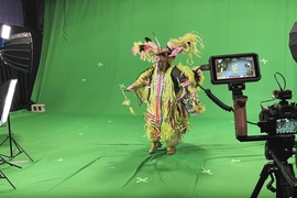 Dancer in Indigenous ceremonial dress front of a green screen