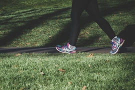 Photo of the legs of a person walking on a path through grass