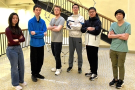 Six students pose with arms folded in front of the Dept. of Mathematics' Chord sculpture. 
