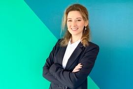 Ana Trišović stands in front of a wall with two aqua color blocks split diagonally