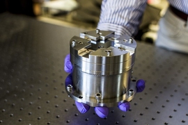 Hand in purple latex gloves holds a cylindrical metal device.