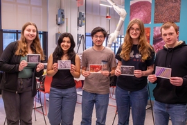 Five MIT students pose holding postcards of their award-winning images.